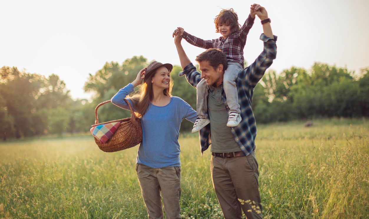 Young caucasian family having a picnic on a grassy field in nature