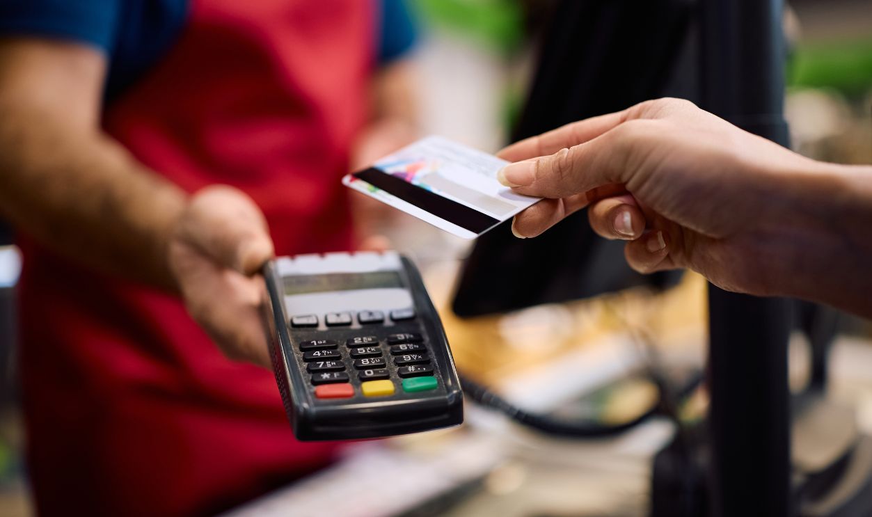Shutterstock-2712374243, Close up of supermarket customer using credit card while paying at cash register.