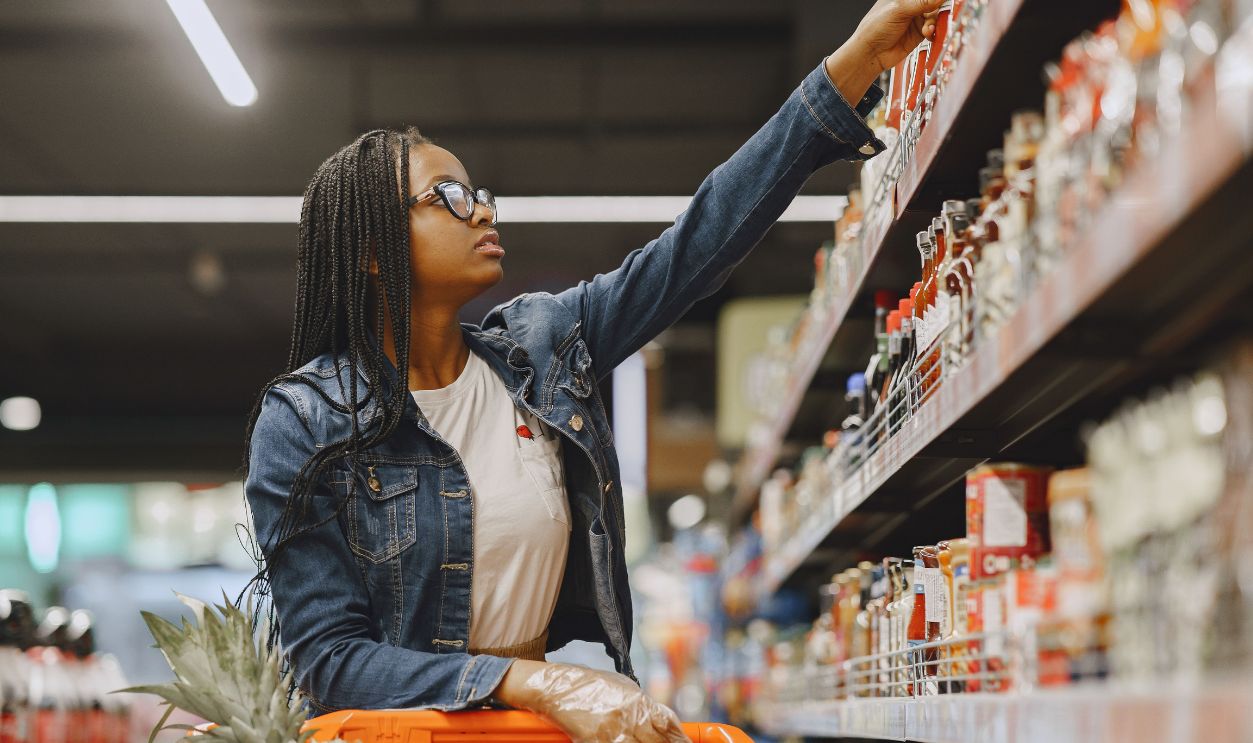 African American woman selecting items in a grocery store aisle