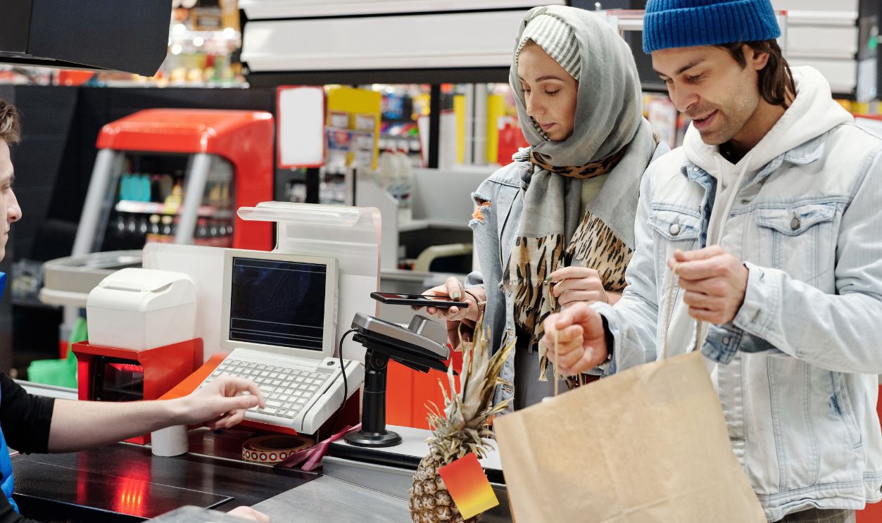 A Middle Eastern couple making a purchase at a supermarket checkout