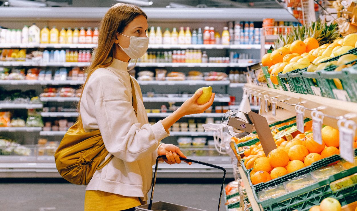 A woman wearing a face mask shops for fruits