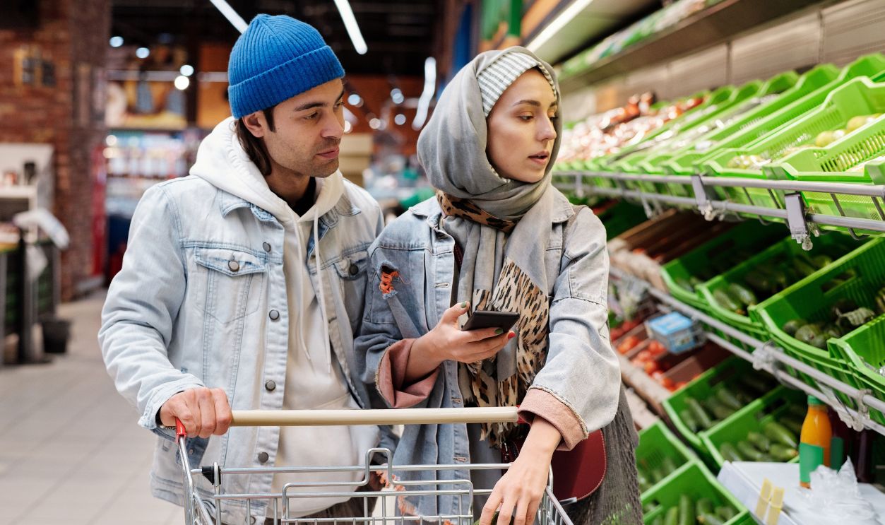 A couple shopping for vegetables in a supermarket, using a smartphone