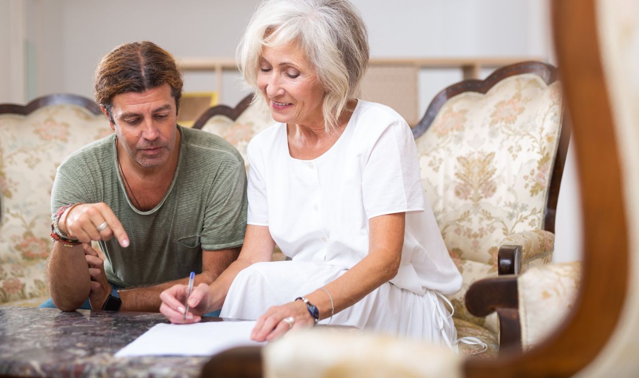 Portrait of elderly woman discussing with her adult son and signing important documents at home