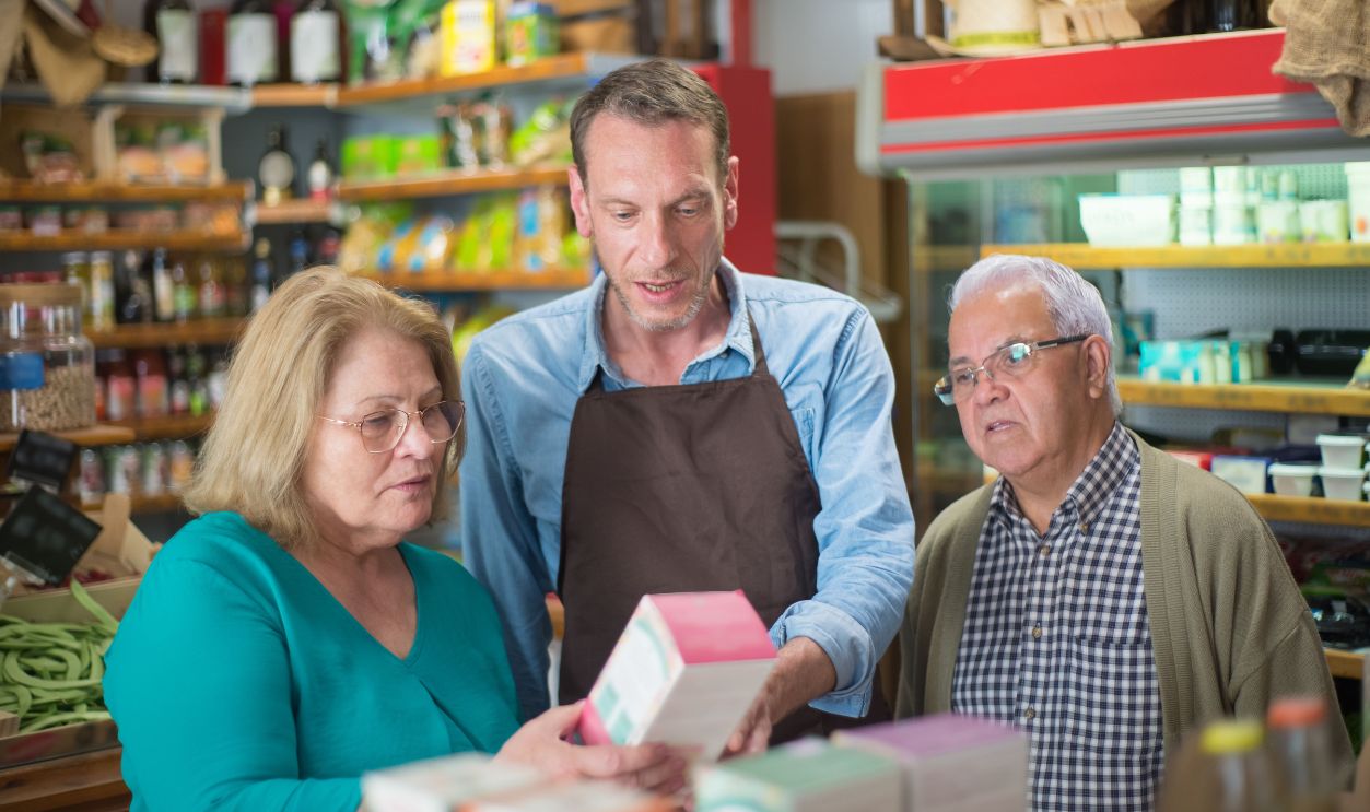 A shopkeeper assists elderly customers in a vibrant Portuguese grocery