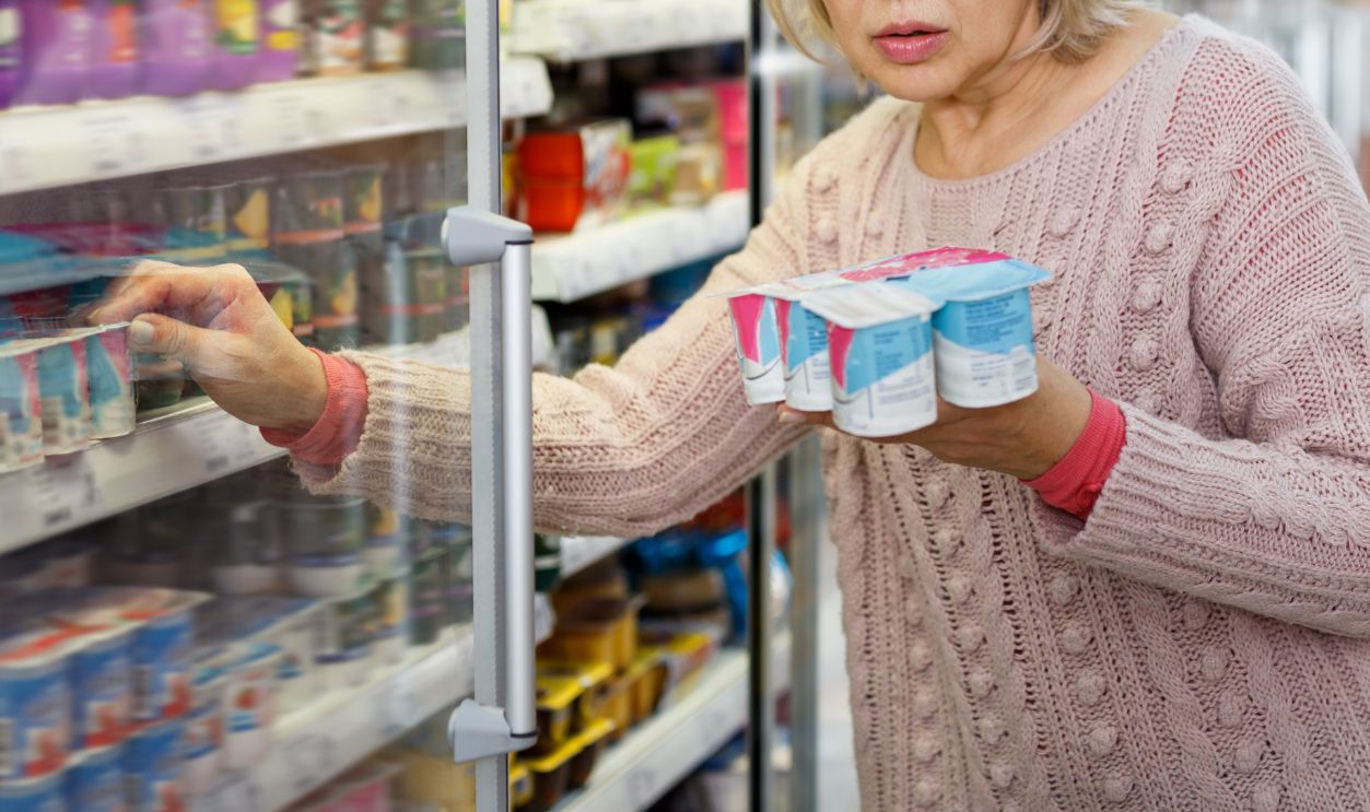 Shocked elderly woman reading product label while choosing groceries in supermarket