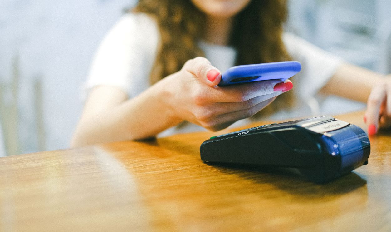 A woman processes a contactless payment using her smartphone at a payment