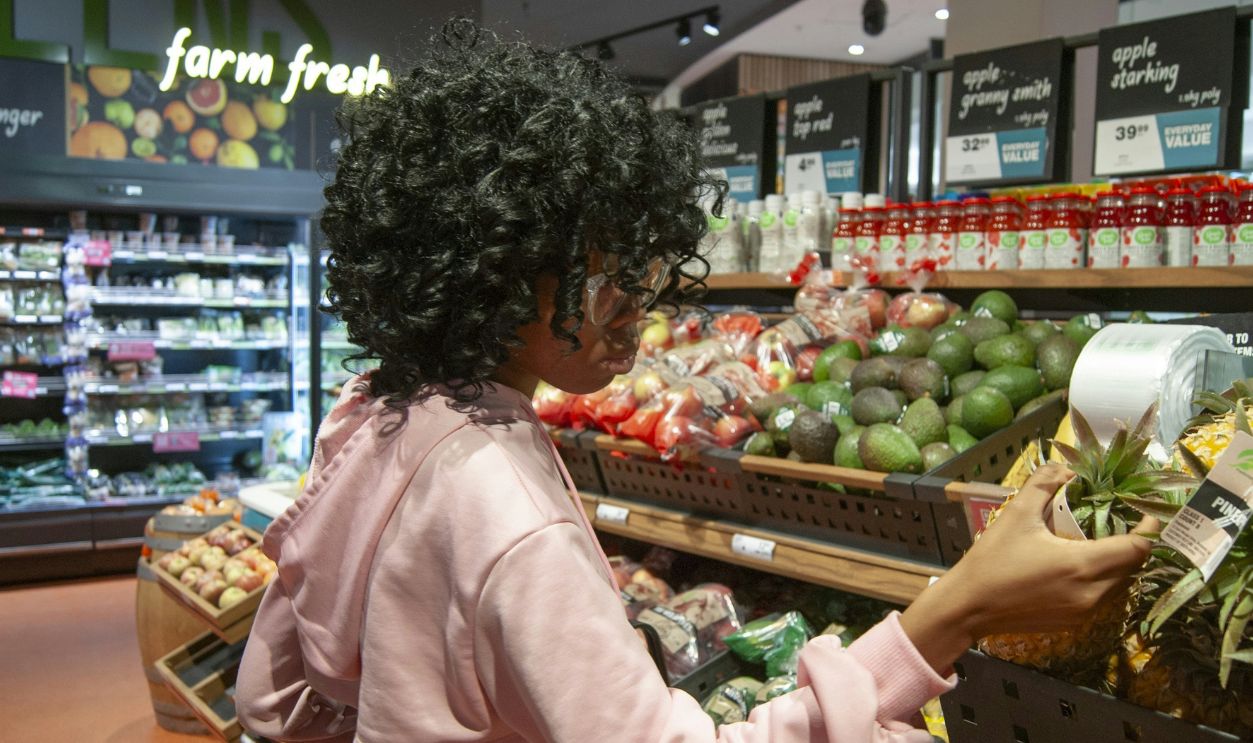 Woman selects pineapple at grocery store