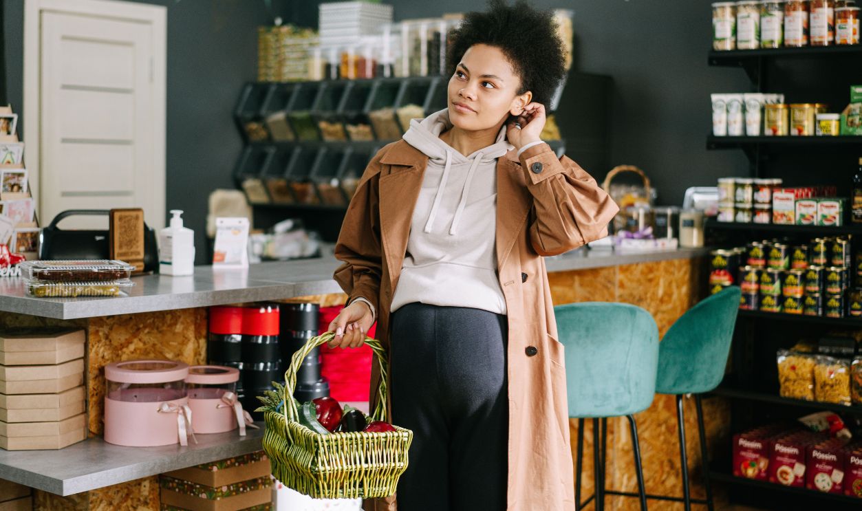 Pregnant woman holding a basket of groceries in a cozy grocery