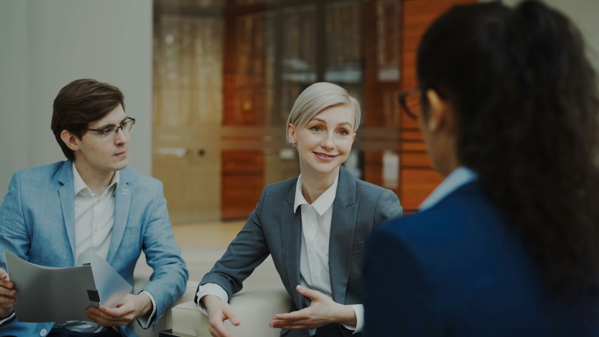 Three people in a business meeting discussing documents