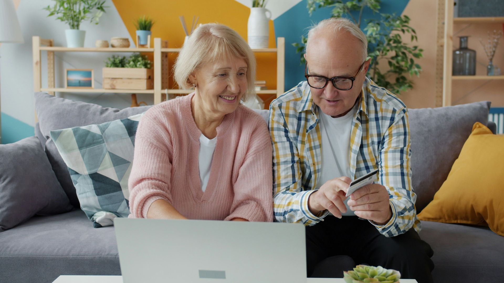 Elderly couple using laptop and credit card at home