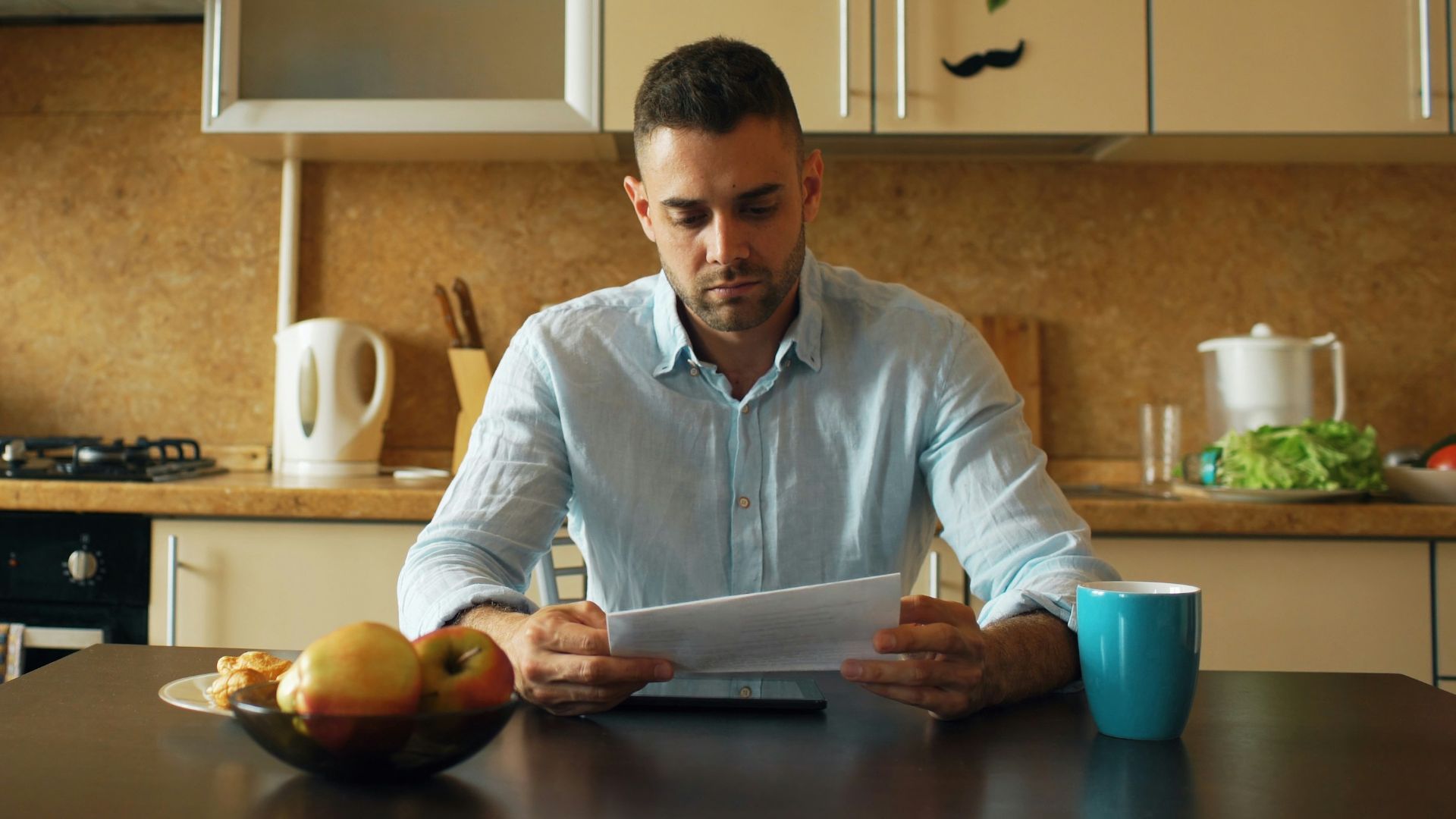 Man reading document at kitchen table with coffee