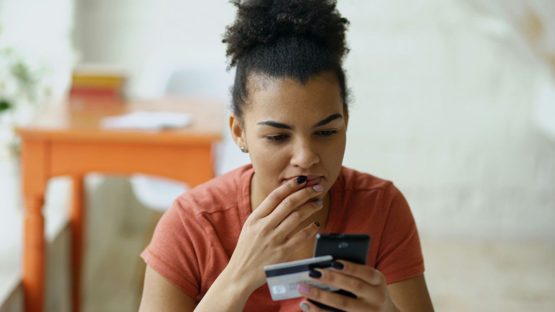 Woman looking at phone with credit card in hand