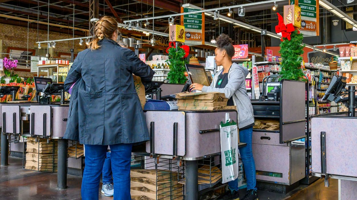 Shutterstock-2397510015, NEW ORLEANS, LA, USA - DECEMBER 5, 2023: Checkout counter with cashier and customers in the Uptown Whole Foods grocery store