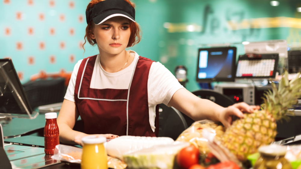 Young upset female cashier in uniform