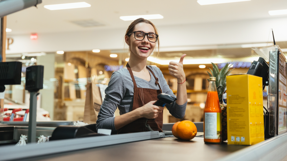 Pretty female cashier scanning grocery items at supermarket