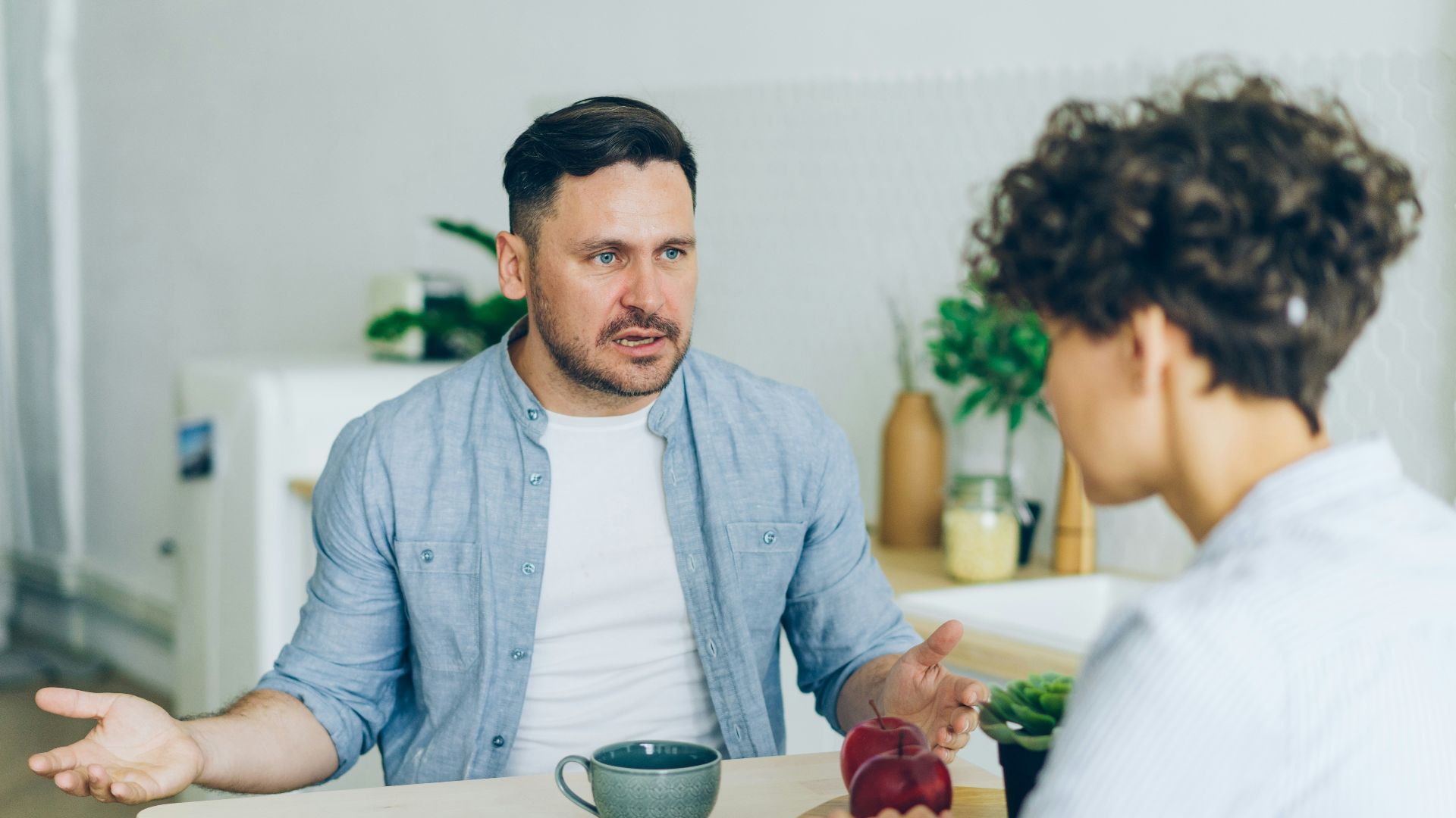 a man sitting at a table talking to a woman