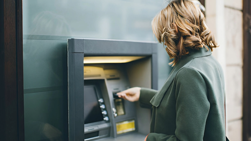Women in Green coat on ATM machine withdrawing cash