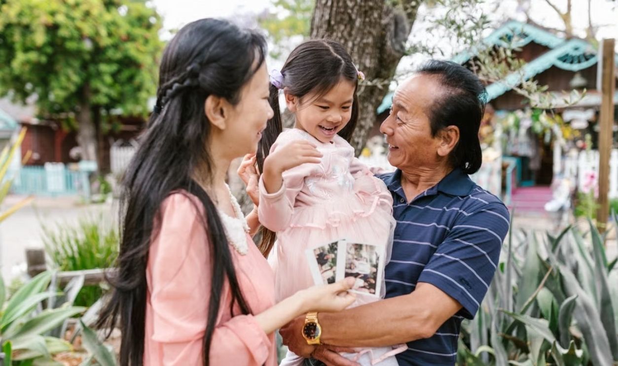 A joyful family scene with grandparents and child bonding outside.