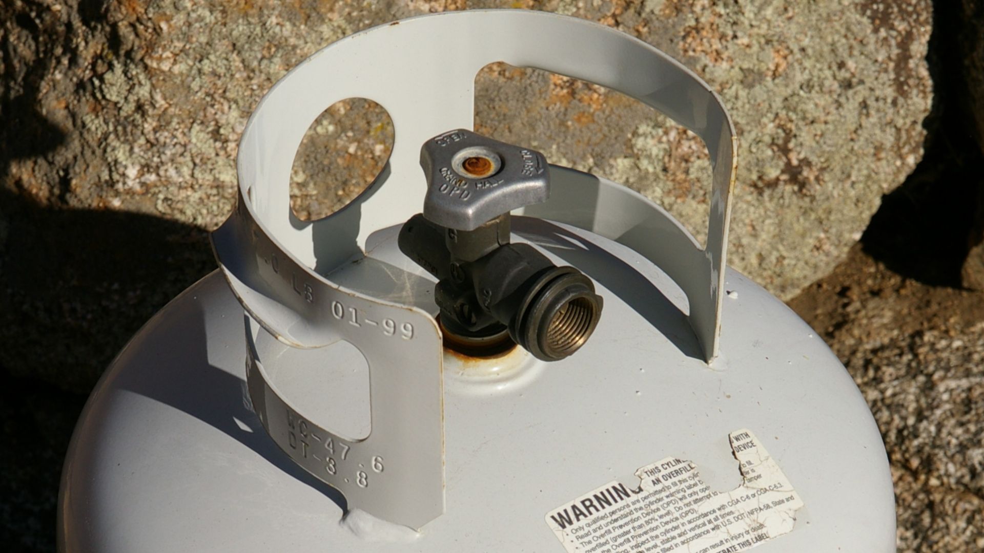 A 20 lb (9.1 kg) steel propane cylinder. This cylinder is fitted with an overfill protection device (OPD) valve, as evidenced by the trilobular handwheel. This cylinder has a water capacity specification of 1,318 in3 (21.60 liter, 5.71 U.S. gallons). P