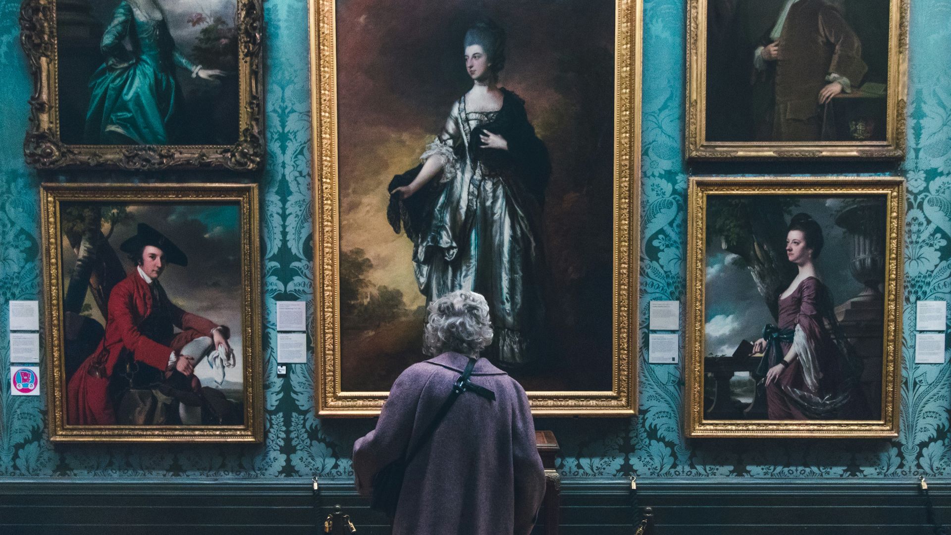 woman looking at painting on wall inside well lit room