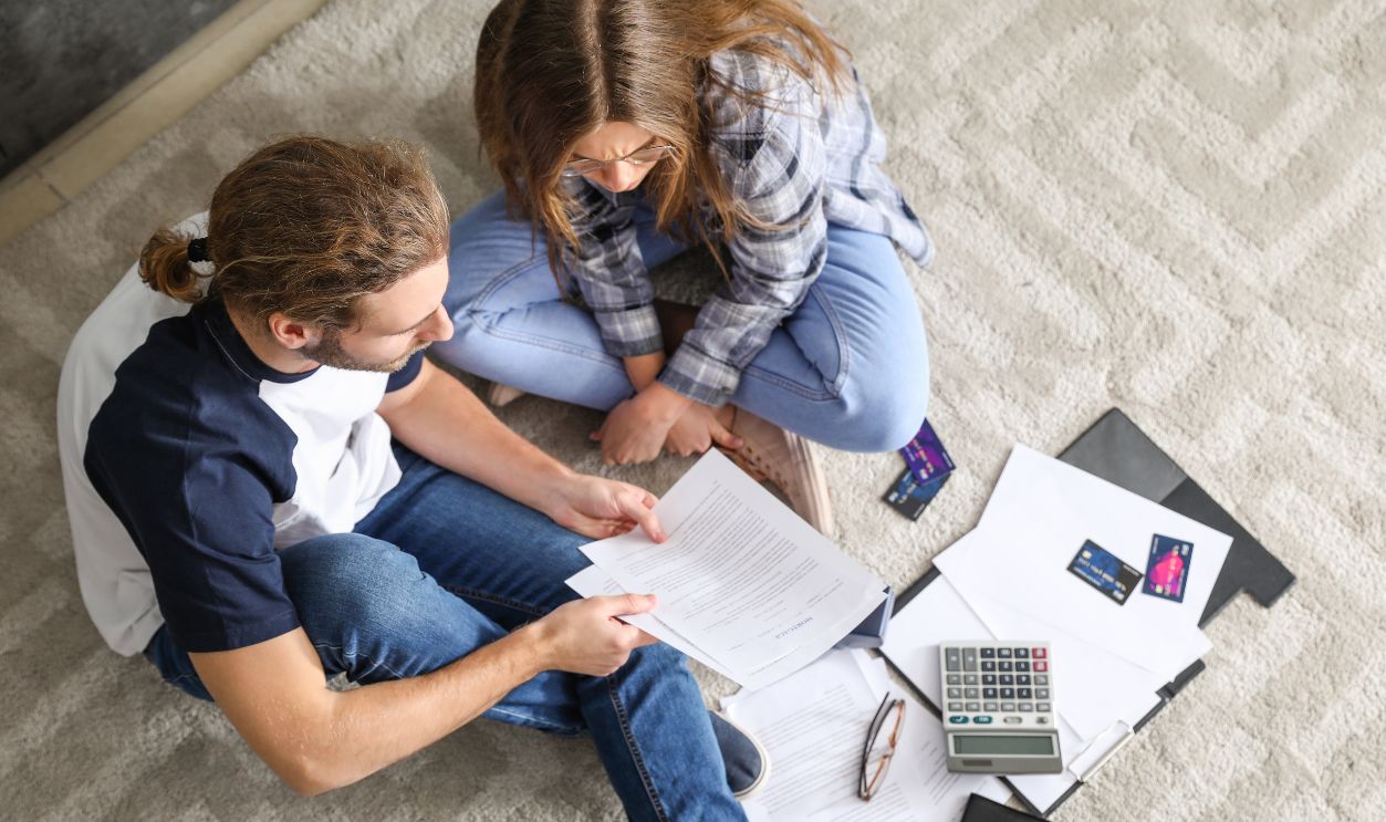 Young couple in debt at home, top view