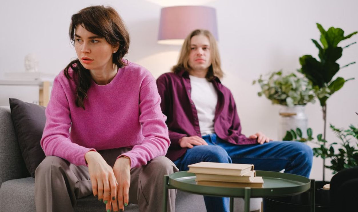 A couple sitting on a sofa with thoughtful expressions, surrounded by home decor
