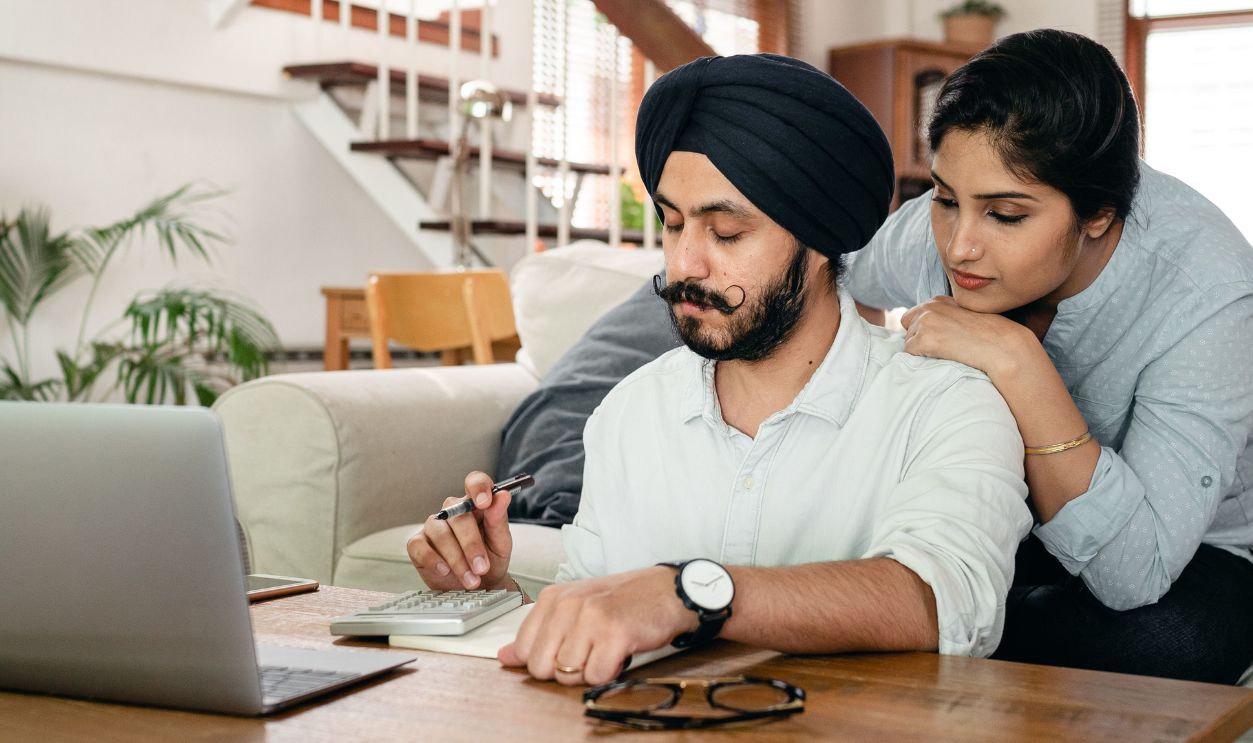 A couple comfortably online shopping at home using a smartphone and tablet for digital purchases.