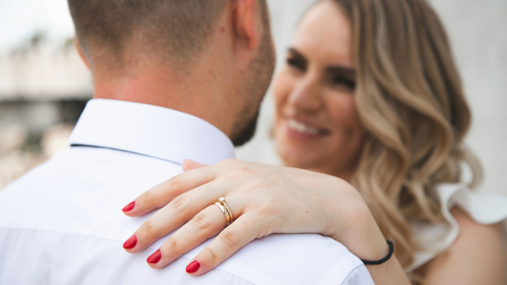 Couple embracing, woman wearing engagement ring