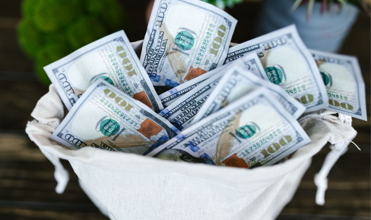 A top view of a sack brimming with US 100 dollar bills, symbolizing wealth and prosperity.