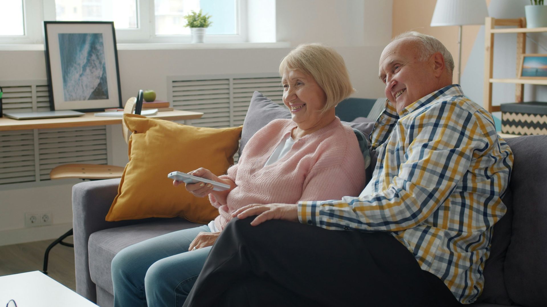 Elderly couple relaxing on a couch watching television