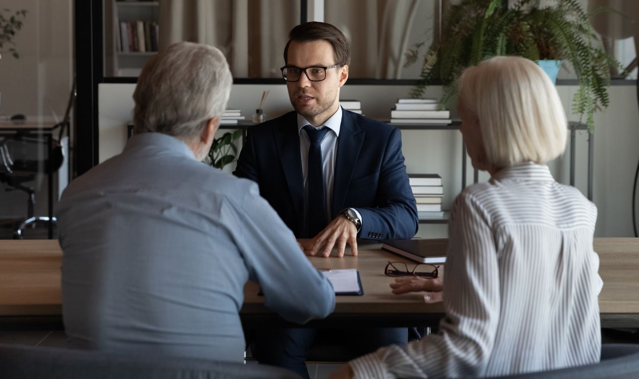 Male Caucasian specialist have meeting with mature couple clients, discuss health insurance for older people. Middle-aged spouses customers consult with relator or broker. Realty, rent concept.