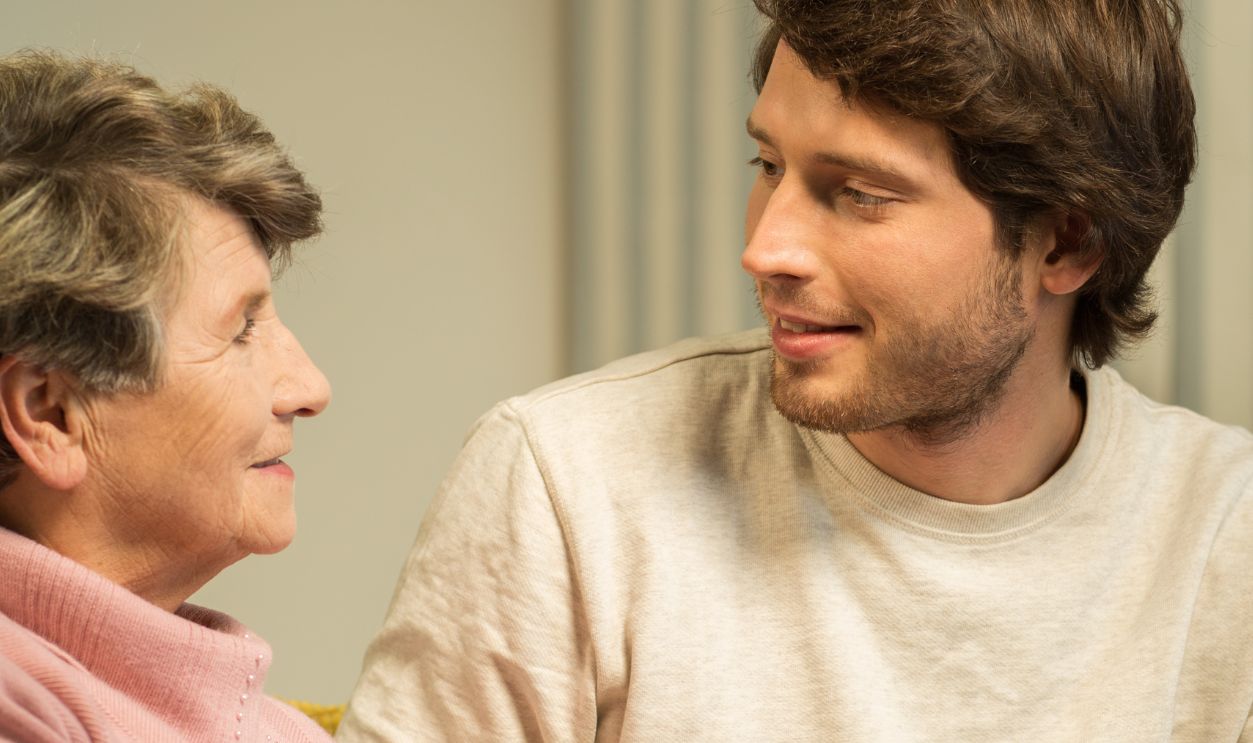Senior woman talking with male handsome caregiver