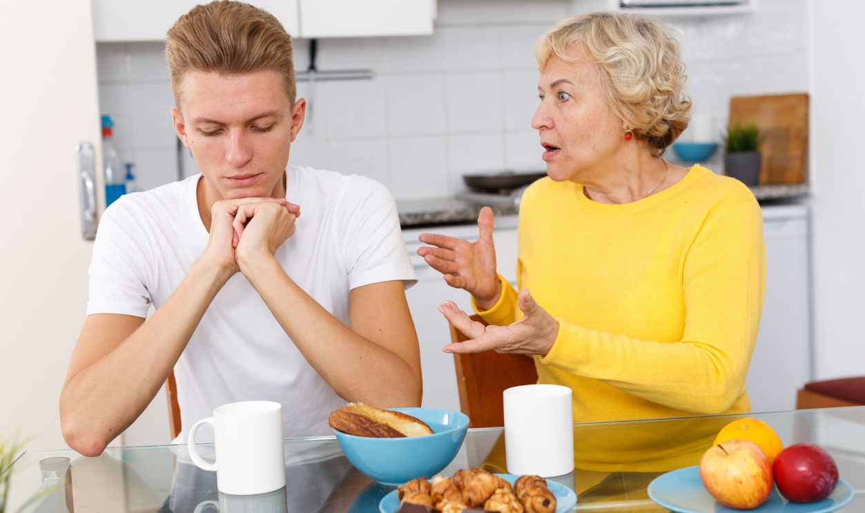 Mature woman scolding her upset adult son in kitchen