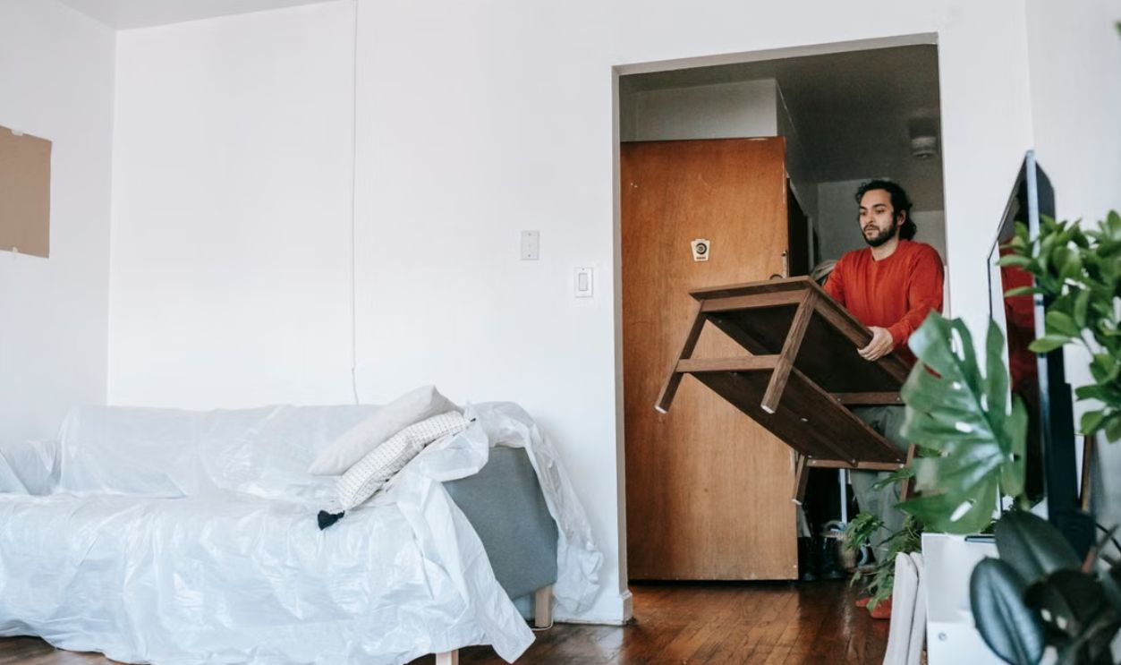 Man holding a wooden table during relocation in a contemporary apartment