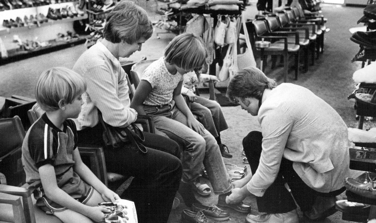 Watching Mark Lyons, assistant manager of KinneyT-(s shoe store in University Hills, fit shoes on Rachel Payne, 8, are, from left, Matthew Payne, 7; Mrs. Mary Payne, and, (behind Ra+?chel), Kristin Payne, 5. Mrs. Payne said Rachel, like her brother, goes to Denver Christian School, 4200 E. Warren Ave.,