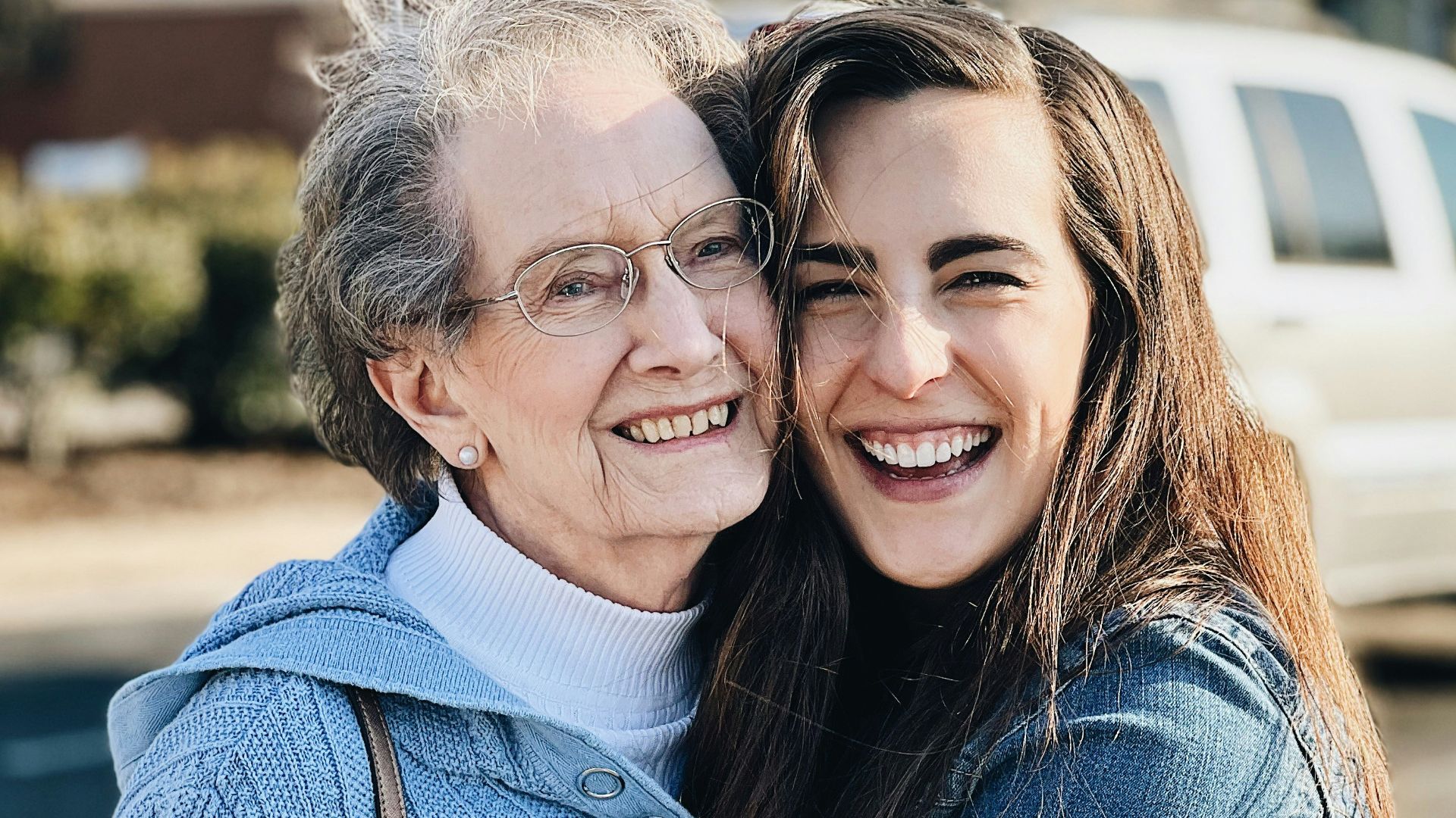 two women hugging each other in a parking lot