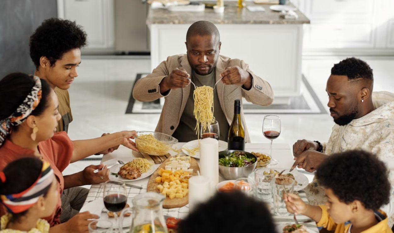 A warm family gathering enjoying dinner together with wine and pasta.