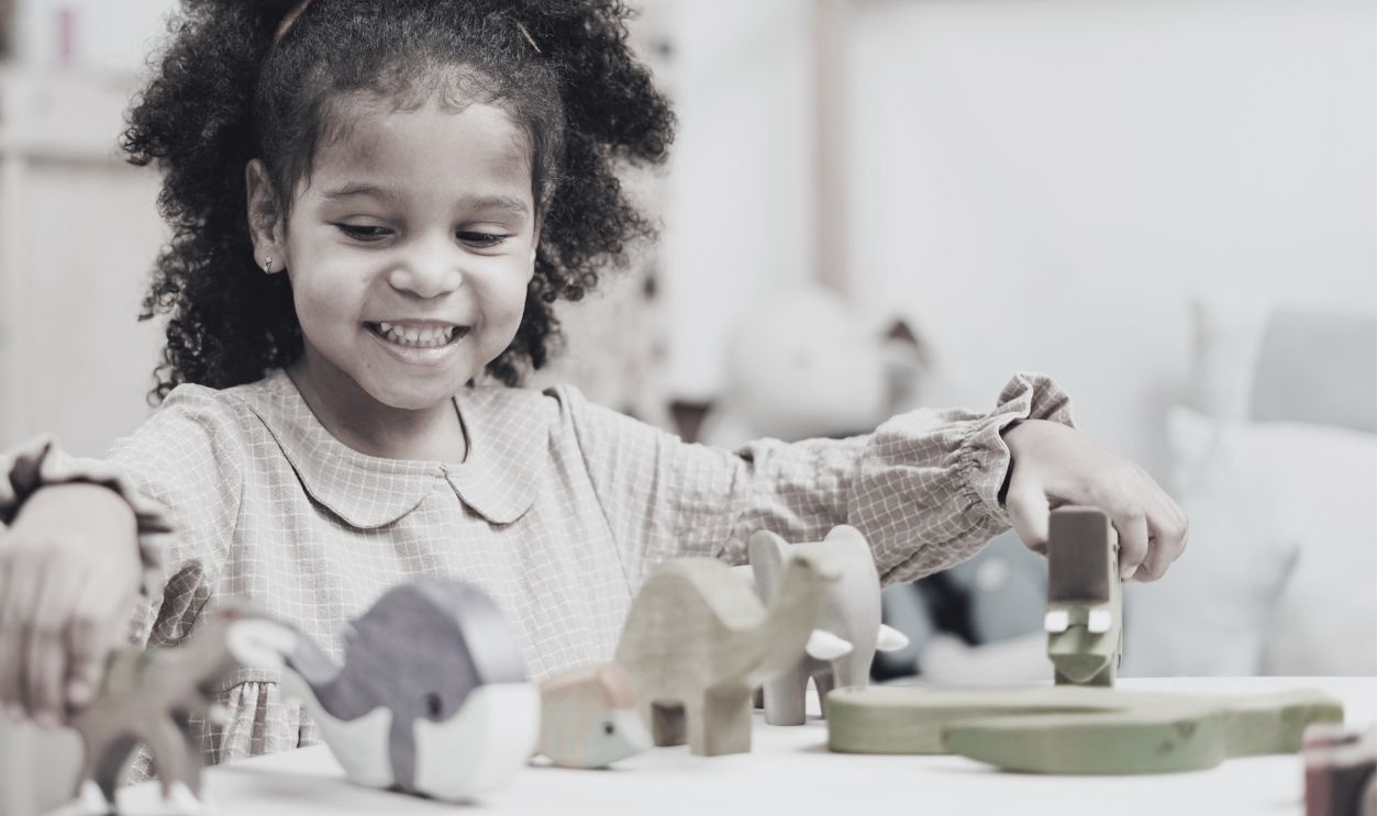 A joyful girl playing with colorful wooden toys at a table
