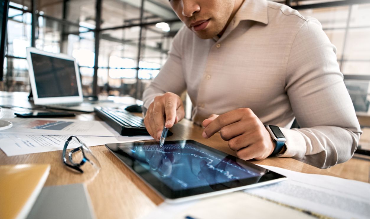 Confident businessman in formalwear pointing at tablet computer