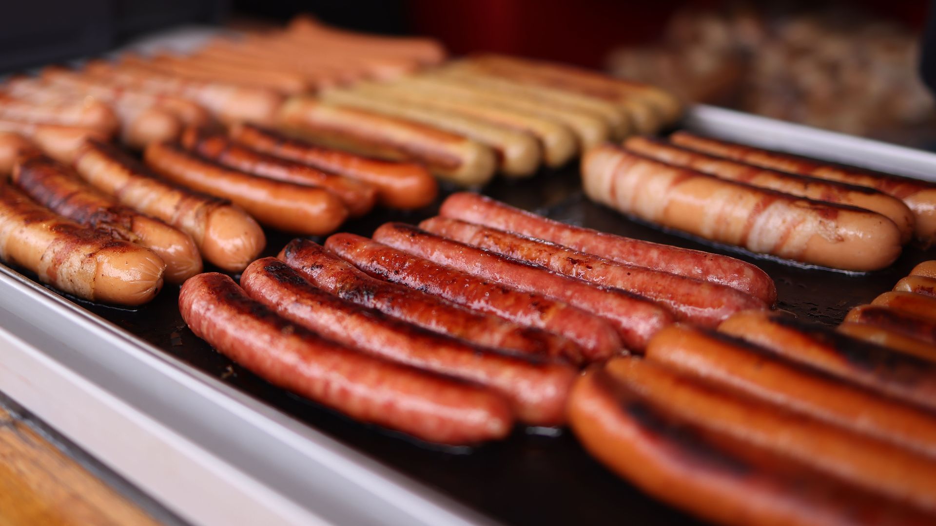 Close-up of assorted sausages sizzling on an outdoor barbecue grill.