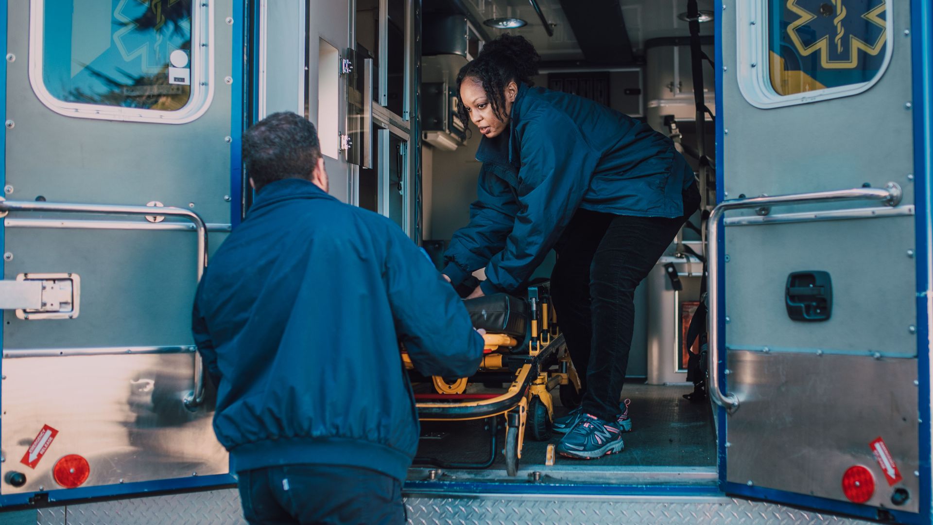 Two paramedics load a stretcher into an ambulance, ready for emergency medical service.