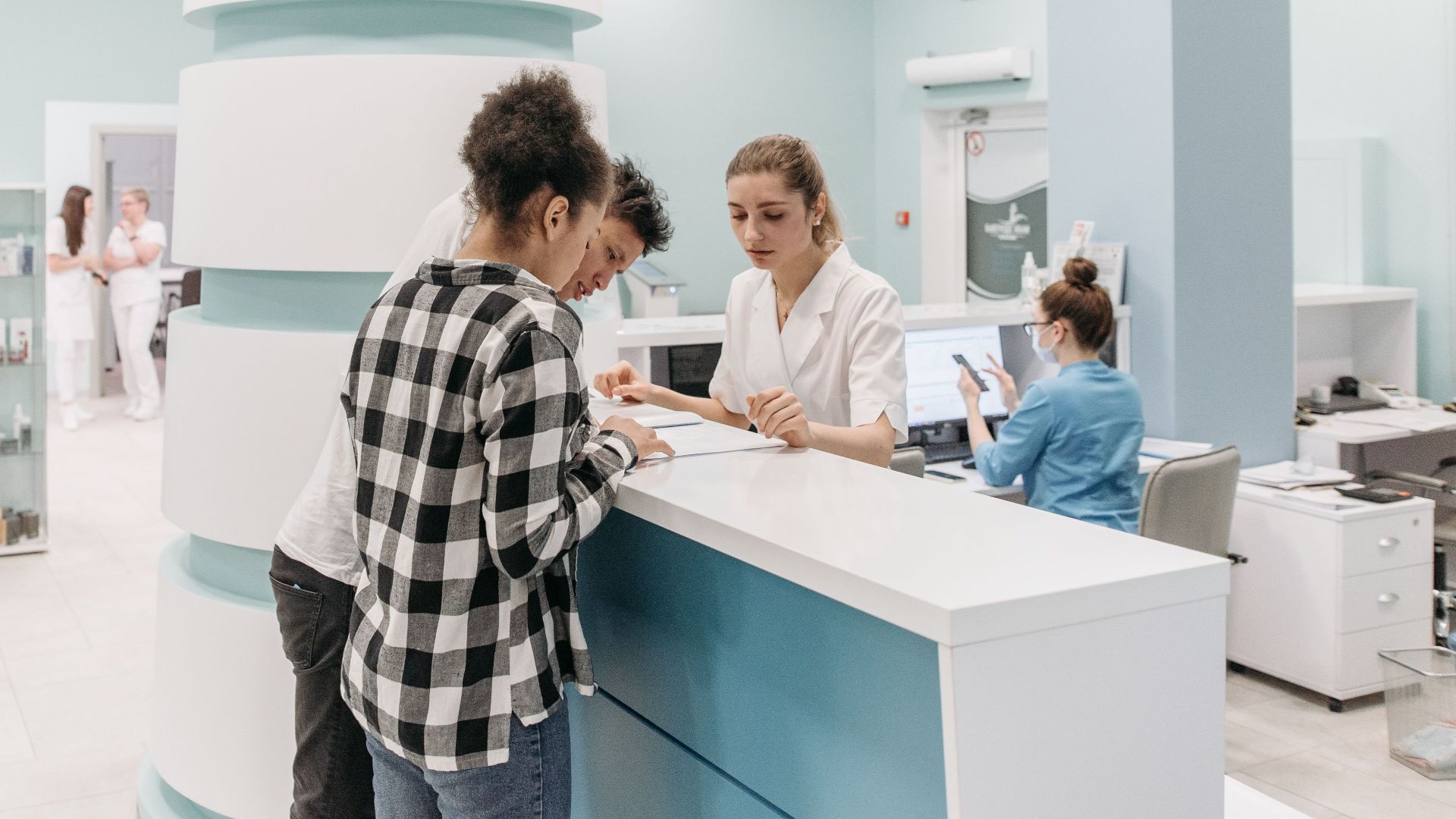 Bright, welcoming clinic reception with patients interacting with staff for registration.