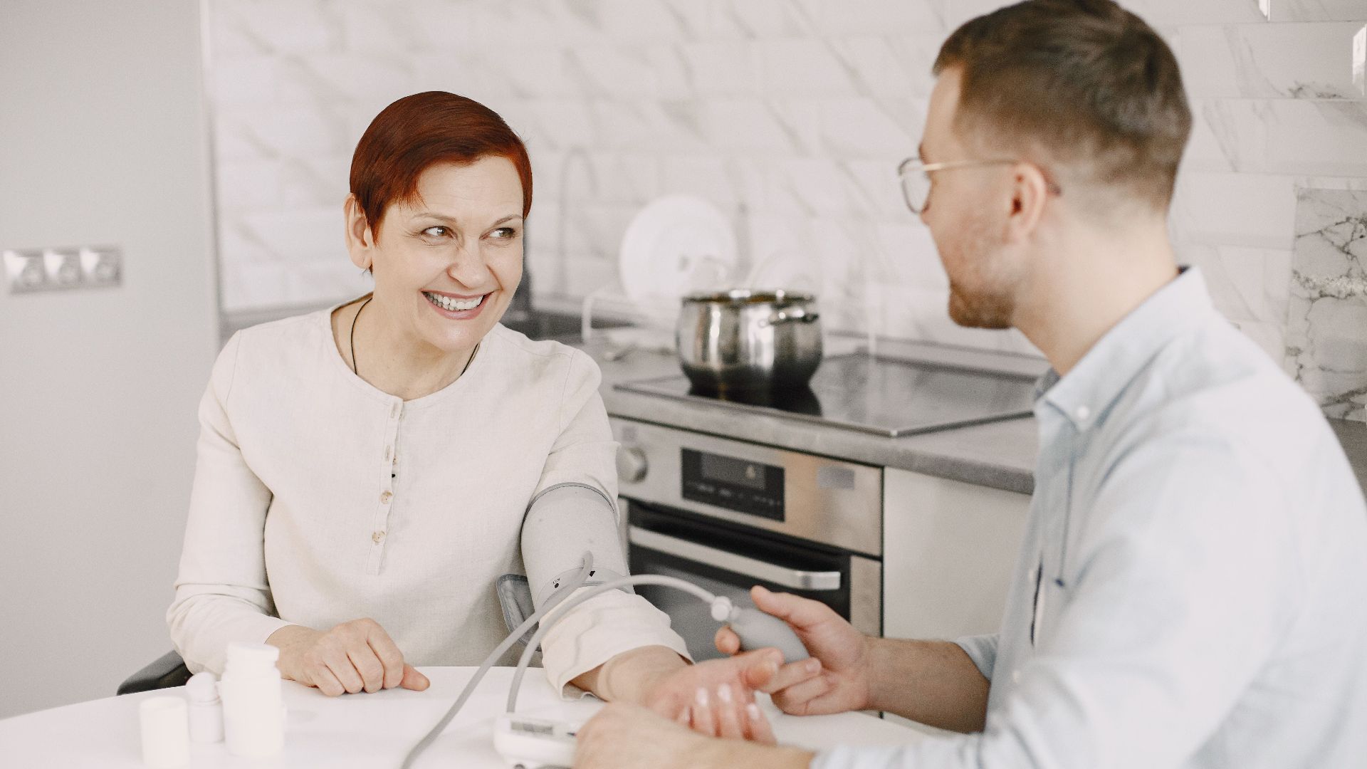 A healthcare professional checks a patient's blood pressure indoors, showcasing a friendly and caring interaction.