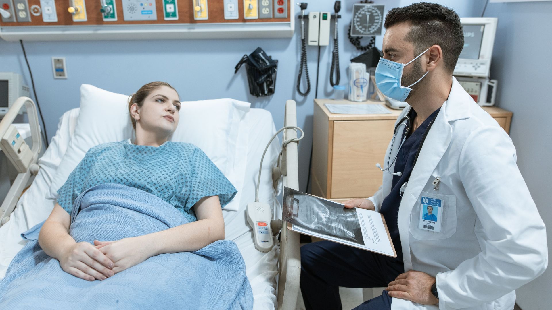 A medical practitioner discusses health details with a patient in a hospital setting.