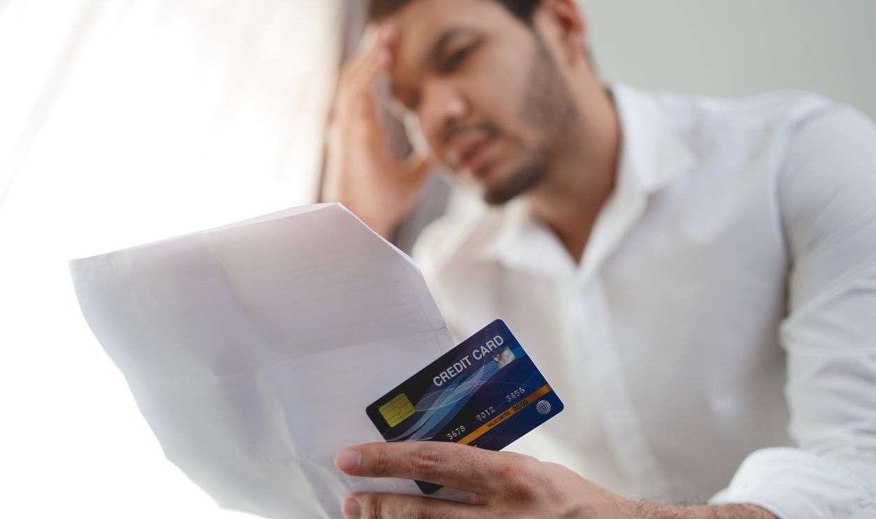 stressed Asian man holding credit card and bill and thinking about finding money to pay credit card debt and all bills. Financial problem concept.