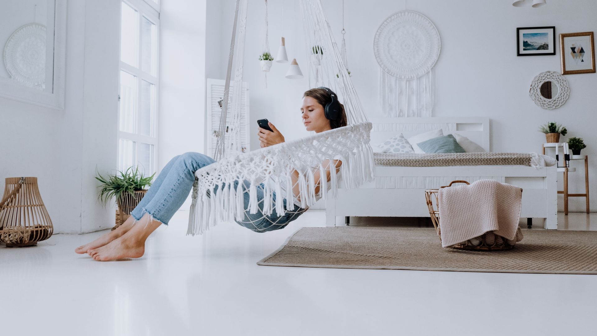 A young woman listening to music in a minimalist bedroom, enjoying a relaxed atmosphere.