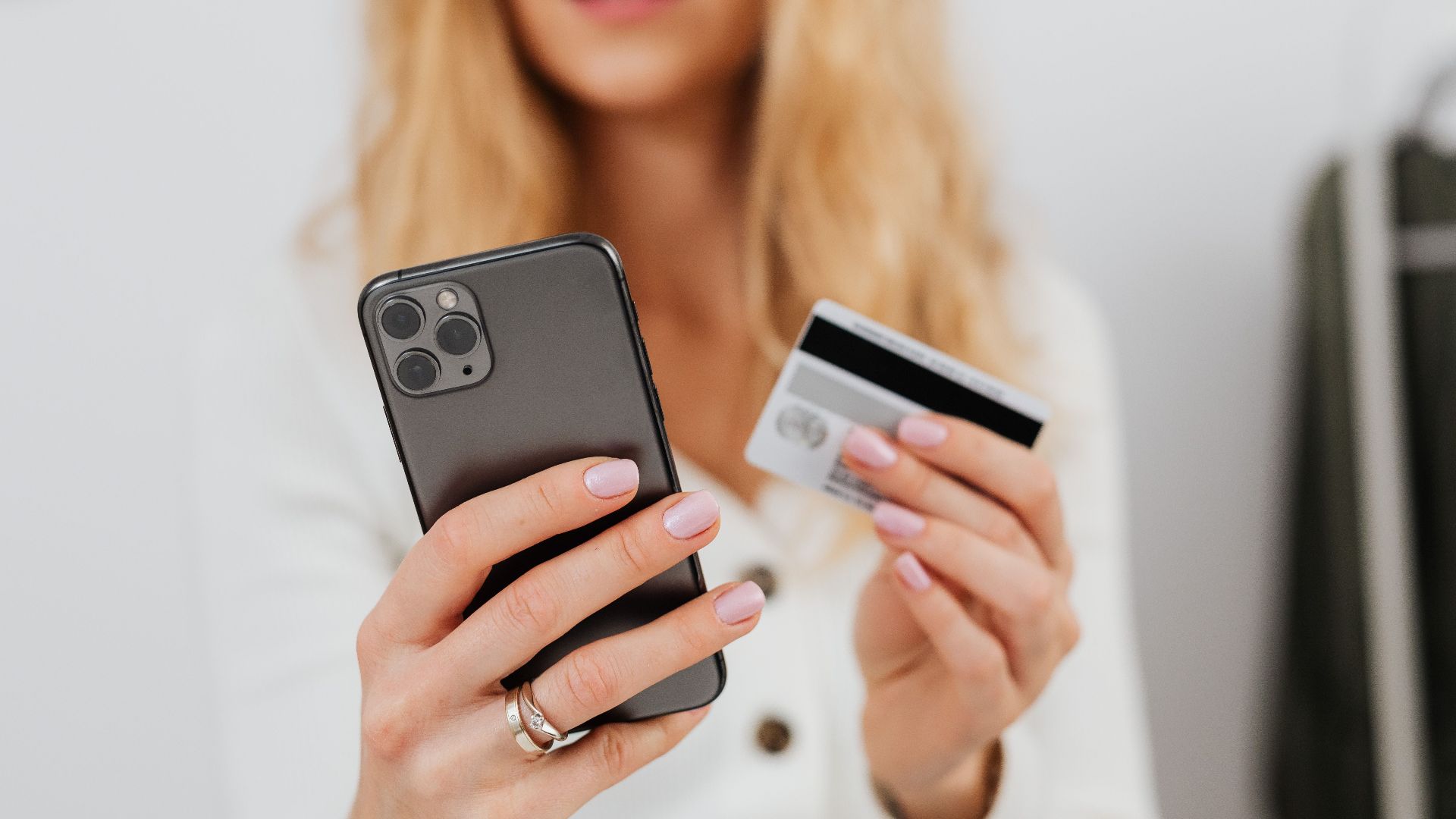 Close-up of a woman using a smartphone and credit card for online shopping.