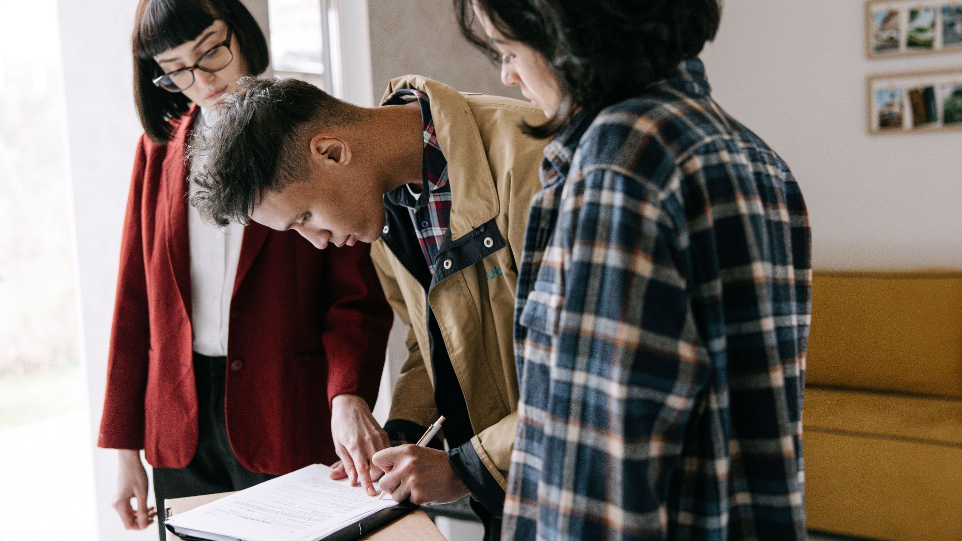 Young couple signing a real estate agreement with an agent indoors.
