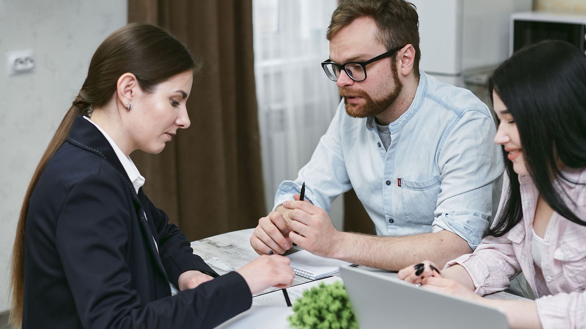 A couple discusses financial documents with their advisor, highlighting investment strategies.