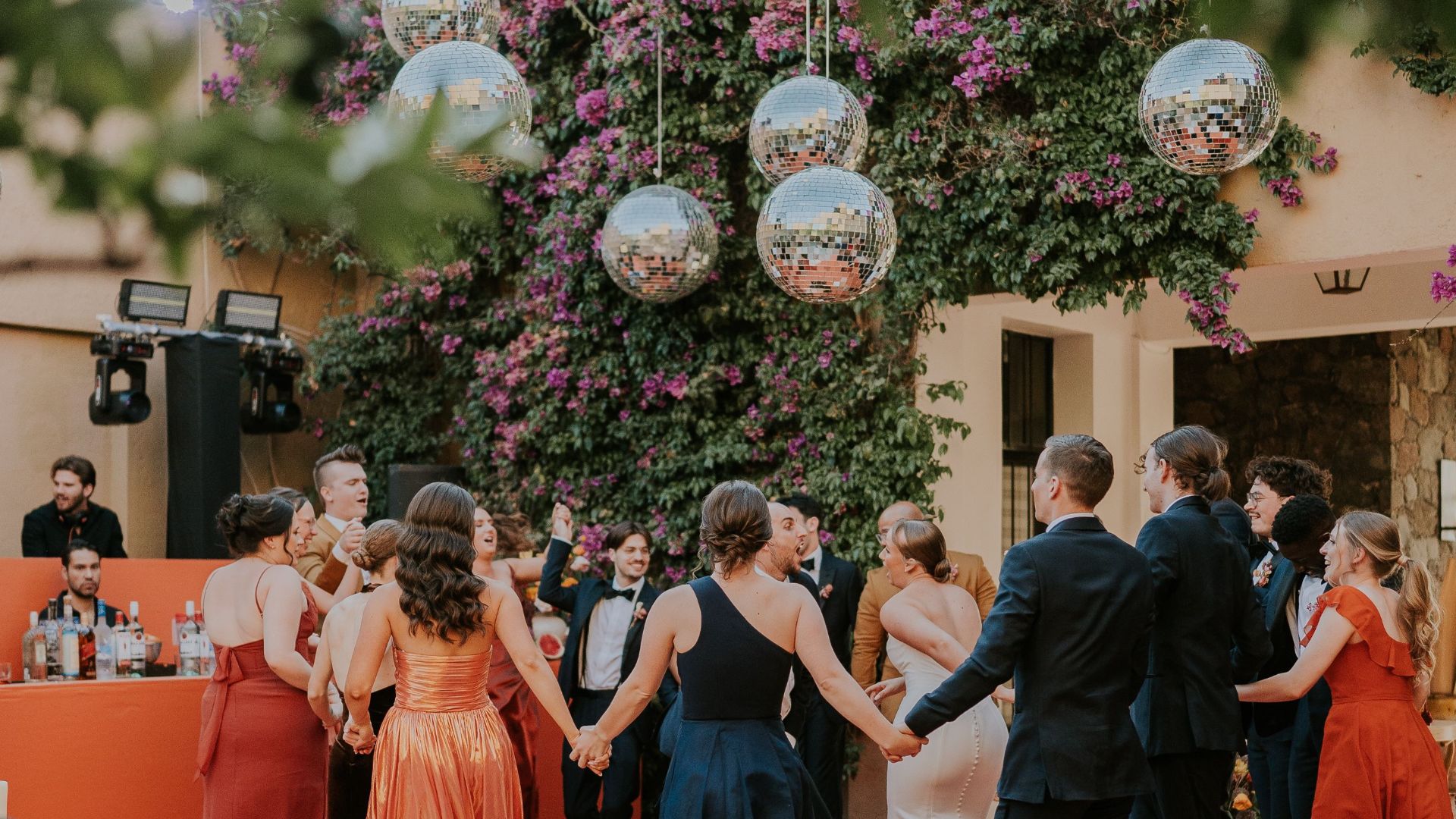 Guests enjoying an elegant outdoor wedding reception with vibrant decorations and floral backdrop.